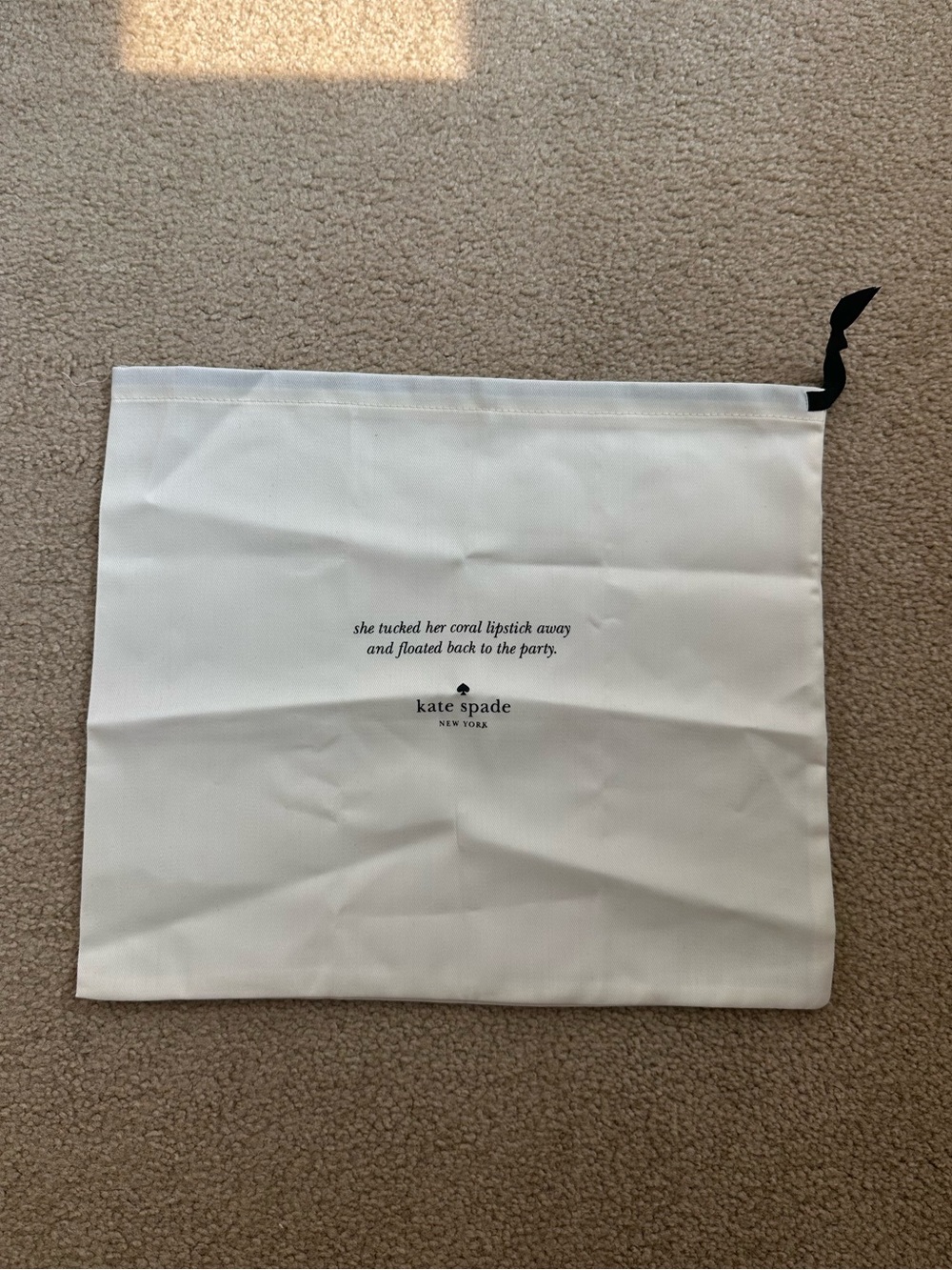 Kate Spade New York cream dust bag with black text and logo